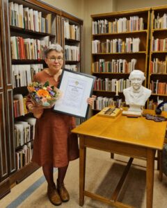 Päivi Heikkilä-Halttunen kukkakimppu ja kunniakirja kädessään.