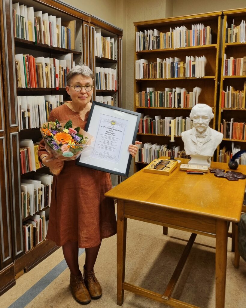 Päivi Heikkilä-Halttunen kukkakimppu ja kunniakirja kädessään.